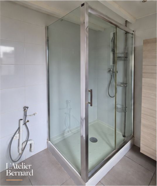 Cabine de douche d’angle en verre et chrome, avec carrelage gris au sol