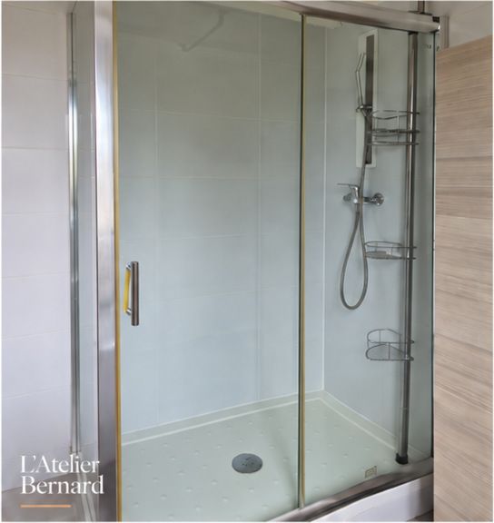 Douche avec porte vitrée coulissante et cadre chromé dans une salle d’eau aux murs clairs