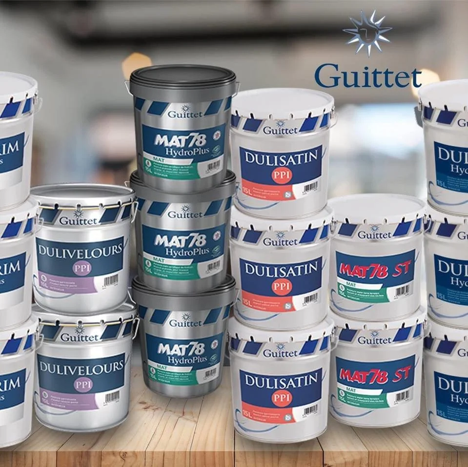 Pots de peinture Guittet, gammes mate et satinée, empilés sur un plan en bois